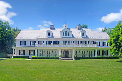 Large traditional two-storey white house exterior in Other with a gable roof and wood siding.