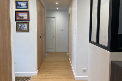 Cette photo montre un couloir tendance avec un mur blanc et parquet clair.
