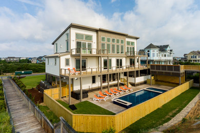 Photo of a large beach style three-storey white house exterior in Other with wood siding, a shed roof and a metal roof.