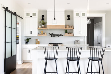 Inspiration for a mid-sized transitional l-shaped medium tone wood floor, multicolored floor and vaulted ceiling eat-in kitchen remodel in Other with an undermount sink, shaker cabinets, white cabinets, quartz countertops, shiplap backsplash, stainless steel appliances, an island and white countertops