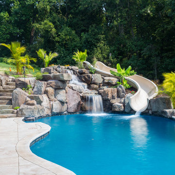 Custom pool with rock waterfalls, water slide & swim up pool bar.