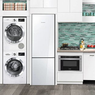 This is an example of a small modern kitchen pantry in Houston with flat-panel cabinets, solid surface benchtops, multi-coloured splashback, ceramic splashback, white appliances, painted wood floors and no island.