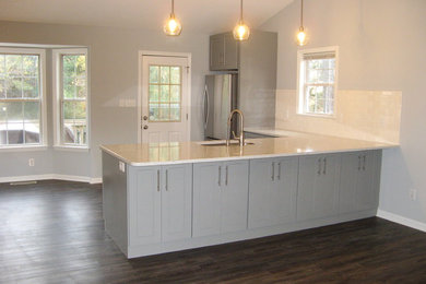 Photo of a mid-sized eclectic kitchen in Raleigh with shaker cabinets, grey cabinets, quartz benchtops, yellow splashback, no island, an undermount sink, stainless steel appliances, dark hardwood floors and brown floor.