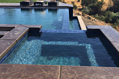 Mid-sized trendy backyard stamped concrete and custom-shaped infinity hot tub photo in Sacramento