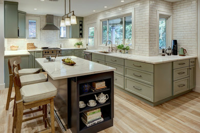Large transitional porcelain tile and brown floor kitchen photo in New York with an undermount sink, shaker cabinets, green cabinets, quartz countertops, beige backsplash, ceramic backsplash, stainless steel appliances, an island and white countertops