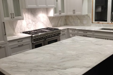 Large transitional l-shaped enclosed kitchen photo in New York with an undermount sink, recessed-panel cabinets, white cabinets, marble countertops, multicolored backsplash, stone slab backsplash, stainless steel appliances and an island