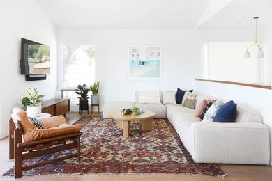Inspiration for a contemporary open concept living room in Los Angeles with white walls, medium hardwood floors, a wall-mounted tv and brown floor.