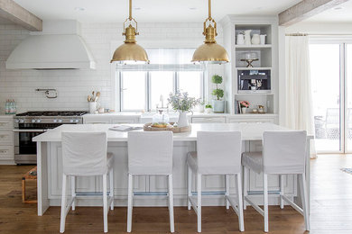 Mid-sized country l-shaped medium tone wood floor and brown floor eat-in kitchen photo in Other with a farmhouse sink, shaker cabinets, gray cabinets, quartz countertops, white backsplash, ceramic backsplash, stainless steel appliances, an island and white countertops