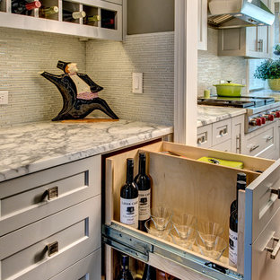 Idées déco pour une grande arrière-cuisine classique en U avec un évier encastré, un placard à porte shaker, des portes de placard grises, un plan de travail en marbre, une crédence blanche, une crédence en carreau de verre, un électroménager en acier inoxydable, un sol en bois brun et un îlot central.