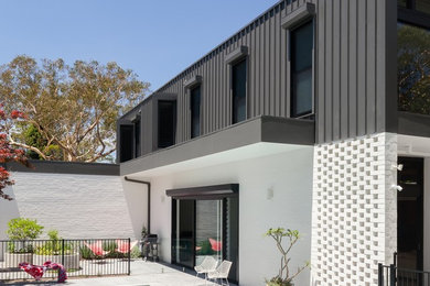 Contemporary two-storey white exterior in Sydney with mixed siding and a flat roof.
