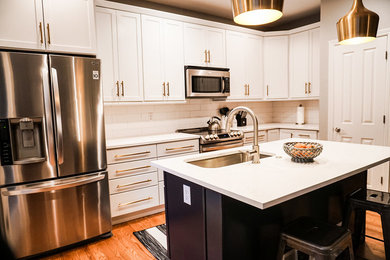 Photo of a small country l-shaped kitchen pantry in Denver with an undermount sink, shaker cabinets, white cabinets, quartz benchtops, white splashback, subway tile splashback, stainless steel appliances, light hardwood floors, with island and brown floor.
