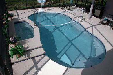 Inspiration for a mid-sized traditional backyard kidney-shaped lap pool in Jacksonville with a hot tub and concrete slab.