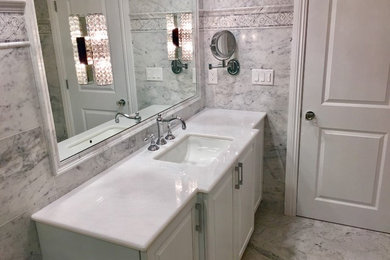 This is an example of a mid-sized transitional master bathroom in Miami with raised-panel cabinets, white cabinets, an open shower, a one-piece toilet, white tile, stone tile, white walls, marble floors, an undermount sink and marble benchtops.