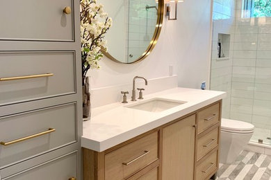 Inspiration for a mid-sized contemporary bathroom in Salt Lake City with recessed-panel cabinets, light wood cabinets, a one-piece toilet, white tile, porcelain tile, porcelain floors, engineered quartz benchtops, a sliding shower screen and white benchtops.
