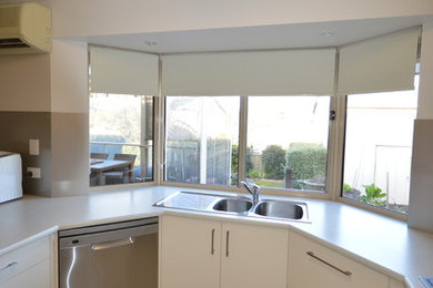 This is an example of a mid-sized modern u-shaped eat-in kitchen in Adelaide with white cabinets, laminate benchtops, beige splashback and glass sheet splashback.
