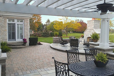 This is an example of a large traditional backyard patio in Chicago with a fire feature, concrete pavers and a pergola.