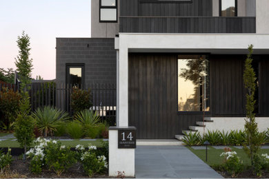 Photo of a modern two-storey grey house exterior in Melbourne with mixed siding, a flat roof, a metal roof and a grey roof.