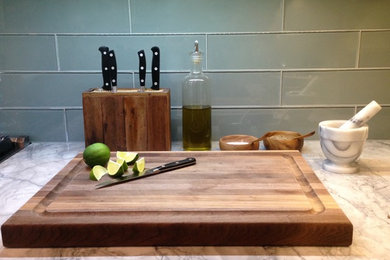 Example of a trendy u-shaped kitchen design in New York with flat-panel cabinets, gray cabinets, marble countertops, gray backsplash, glass tile backsplash, stainless steel appliances and a peninsula