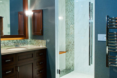 Bathroom - large transitional gray tile and glass sheet porcelain tile bathroom idea in Las Vegas with recessed-panel cabinets, medium tone wood cabinets, an undermount sink, quartz countertops, a one-piece toilet and blue walls