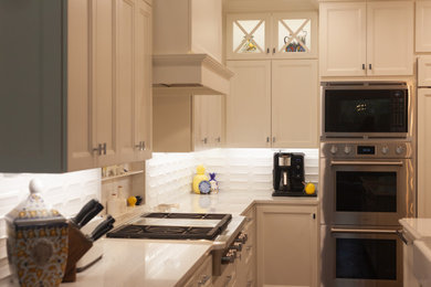 ダラスにある高級な巨大なトラディショナルスタイルのおしゃれなキッチン (エプロンフロントシンク、シェーカースタイル扉のキャビネット、白いキャビネット、クオーツストーンカウンター、白いキッチンパネル、サブウェイタイルのキッチンパネル、シルバーの調理設備、濃色無垢フローリング、白いキッチンカウンター) の写真