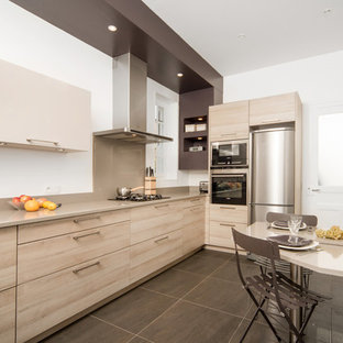 Imagen de cocina comedor en L, contemporánea, grande, con fregadero bajoencimera, armarios con paneles lisos, puertas de armario de madera clara y electrodomésticos de acero inoxidable