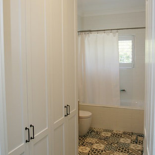 Photo of a medium sized shabby-chic style single-wall utility room in Sydney with shaker cabinets, white cabinets, composite countertops, white walls, ceramic flooring, a submerged sink, white worktops, an integrated washer and dryer and multi-coloured floors.