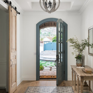 フェニックスの片開きドアカントリー風おしゃれな玄関ドア (白い壁、淡色無垢フローリング、青いドア、ベージュの床) の写真