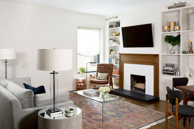 Inspiration for a mid-sized transitional open concept living room in New York with a library, white walls, a standard fireplace, a brick fireplace surround, a wall-mounted tv and multi-coloured floor.