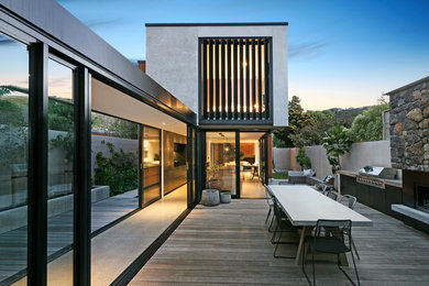This is an example of a contemporary backyard deck in Christchurch with with fireplace and no cover.