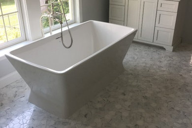 Example of a mid-sized classic master gray tile and marble tile marble floor and white floor freestanding bathtub design in Other with shaker cabinets, white cabinets, gray walls, marble countertops, a two-piece toilet and a drop-in sink