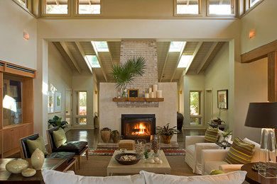 Inspiration for a mid-sized rustic open concept medium tone wood floor living room remodel in Miami with beige walls, a standard fireplace, a plaster fireplace and a concealed tv