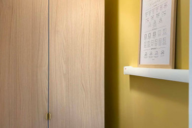 Aménagement d'une petite buanderie méditerranéenne en L et bois clair avec un plan de travail en bois, un mur jaune, parquet clair et des machines superposées.