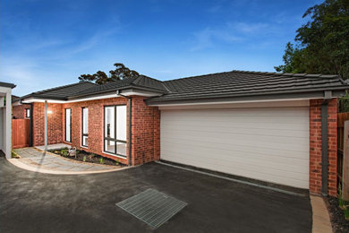 Photo of a small modern one-storey brick red house exterior in Melbourne with a gable roof and a tile roof.