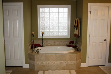 Inspiration for a large timeless master drop-in bathtub remodel in Nashville with raised-panel cabinets, medium tone wood cabinets, beige walls and an undermount sink
