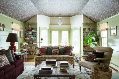Photo of a mid-sized eclectic living room in New York with a library, green walls, light hardwood floors and a standard fireplace.