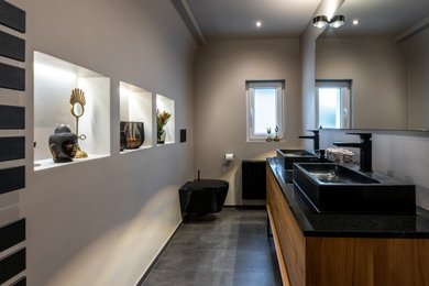 Foto på ett mellanstort funkis svart badrum med dusch, med skåp i mellenmörkt trä, en kantlös dusch, en vägghängd toalettstol, beige väggar, ett fristående handfat, granitbänkskiva, grått golv och med dusch som är öppen