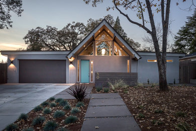 Example of a large 1960s gray one-story stucco exterior home design in Portland with a shingle roof