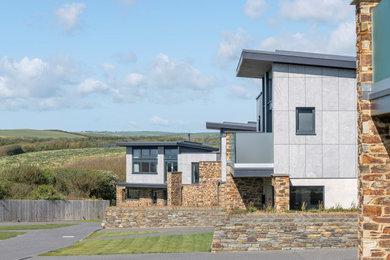 This is an example of a large contemporary two floor detached house in Cornwall with mixed cladding, a flat roof, a metal roof and a grey roof.