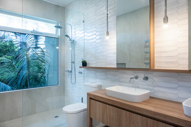 Design ideas for a large contemporary master bathroom in Melbourne with medium wood cabinets, an open shower, a one-piece toilet, white tile, ceramic tile, white walls, porcelain floors, a drop-in sink, laminate benchtops, beige floor, an open shower, brown benchtops and flat-panel cabinets.