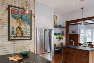 Inspiration for a mid-sized industrial l-shaped light wood floor and beige floor open concept kitchen remodel in New York with an undermount sink, shaker cabinets, dark wood cabinets, soapstone countertops, white backsplash, stone slab backsplash, stainless steel appliances and a peninsula