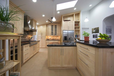 Trendy porcelain tile kitchen photo in Albuquerque with an undermount sink, recessed-panel cabinets, light wood cabinets, granite countertops, beige backsplash, porcelain backsplash, stainless steel appliances and an island