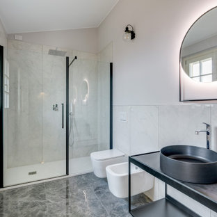 Foto di una stanza da bagno padronale design con ante nere, WC sospeso, piastrelle bianche, piastrelle di marmo, pareti bianche, pavimento in marmo, lavabo a bacinella, pavimento grigio, porta doccia a battente, top nero, un lavabo e mobile bagno freestanding