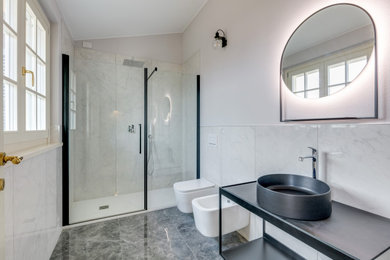 Foto di una stanza da bagno padronale design con ante nere, WC sospeso, piastrelle bianche, piastrelle di marmo, pareti bianche, pavimento in marmo, lavabo a bacinella, pavimento grigio, porta doccia a battente, top nero, un lavabo e mobile bagno freestanding