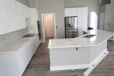 Example of a large minimalist kitchen design in Miami with shaker cabinets, quartz countertops, an island, an undermount sink and stainless steel appliances