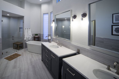 Bathroom - transitional master gray tile and ceramic tile vinyl floor bathroom idea in Phoenix with shaker cabinets, black cabinets, white walls, an undermount sink and solid surface countertops