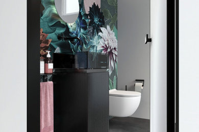 Photo of a small contemporary bathroom in Other with glass-front cabinets, black cabinets, a wall mounted toilet, multi-coloured walls, a pedestal sink, glass worktops, black worktops, a single sink, a freestanding vanity unit and wallpapered walls.
