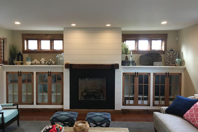 Large mountain style open concept dark wood floor and brown floor family room photo in Denver with beige walls, a standard fireplace and a wood fireplace surround