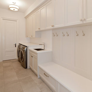 ロサンゼルスの中サイズのコンテンポラリースタイルのおしゃれな家事室 (アンダーカウンターシンク、シェーカースタイル扉のキャビネット、白いキャビネット、クオーツストーンカウンター、白い壁、ライムストーンの床、左右配置の洗濯機・乾燥機) の写真