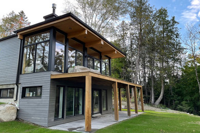 Foto de fachada de casa gris y negra minimalista de tamaño medio de dos plantas con revestimiento de madera, tejado plano, tejado de varios materiales y tablilla
