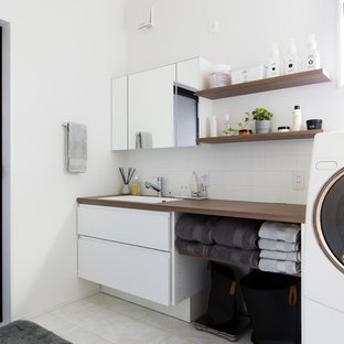 名古屋のおしゃれな洗濯室 (ドロップインシンク、フラットパネル扉のキャビネット、白いキャビネット、木材カウンター、白い壁、ベージュの床、茶色いキッチンカウンター) の写真